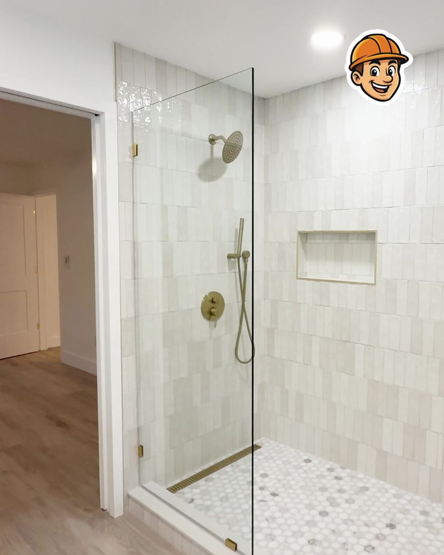 A new walk-in shower with white tile and a glass panel